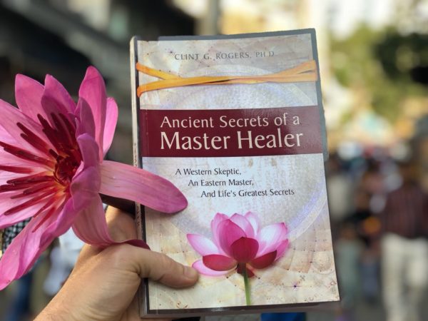 Ancient Secrets of a Master Healer book held with a lotus blossom.
