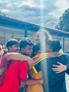 Group of orlder Nepali oprhan boys in a group hug with Dr. Clint Rogers.